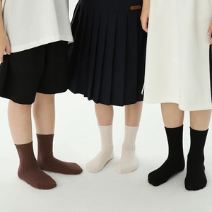 Three children wearing ribbed cotton crew socks in brown, beige, and black colors