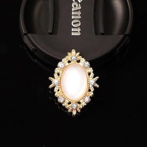 Macro detail of a vintage gold alloy brooch with white opal and sparkly rhinestones