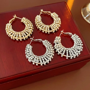 Close-up of gold and silver rhinestone hoop earrings presented on a wooden jewelry box
