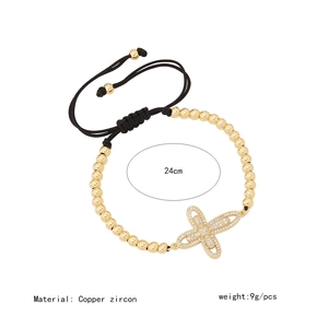 Detail view of gold beaded bracelet with zircon butterfly charm and adjustable black cord