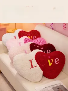 Detail of plush heart-shaped pillows with I Love embroidery on a white leather sofa