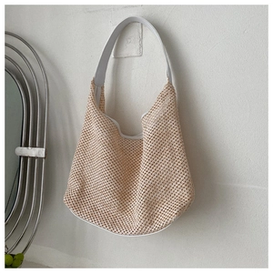 Detail of hollow-out woven texture and contrast white PU shoulder strap of the beach bag