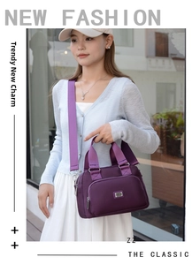 Detail of a large purple nylon shoulder bag with a high-quality metal logo and wide strap