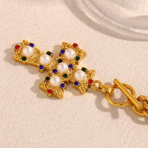 Detail of 18K gold-plated cross necklace with white pearls and colorful gemstones