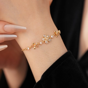 Gros plan sur un bracelet doré à fleurs serti de zircons porté sur un fond noir élégant