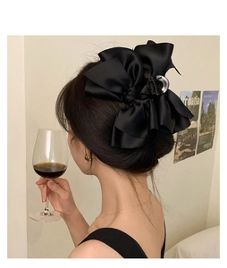 Detail of elegant black satin multi-layer bow hair claw clip worn by model in a chic setting