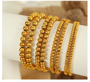 Detail view of gold beaded titanium steel bracelets in four different sizes on display