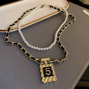 Détail de chaîne dorée avec cuir noir et pendentif numéro 5 serti de diamants