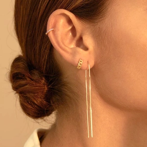 Detailed close-up of layered gold chain hoop earrings and zircon ear cuff on ear