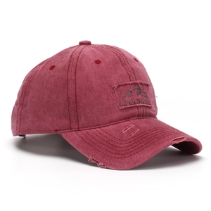 Detail of burgundy washed cotton baseball cap featuring vintage frayed edges and logo patch