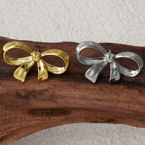 Détail de boucles d'oreilles nœud en acier inoxydable doré et argenté sur bois