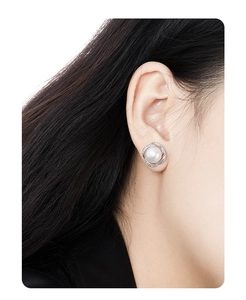 Macro side view of a S925 silver pearl earring with zircon border worn on a model ear