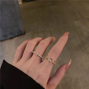 Detailed view of elegant silver cross ring and gold heart chain ring with crystals
