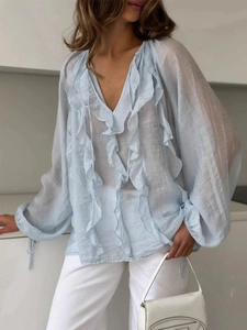 Detail of V-neck light blue blouse with ruffles and drawstring lantern sleeves
