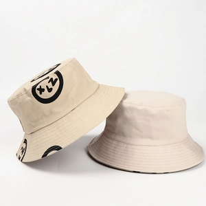 Close-up of beige cotton bucket hats showing graffiti smiley print and parallel brim stitching