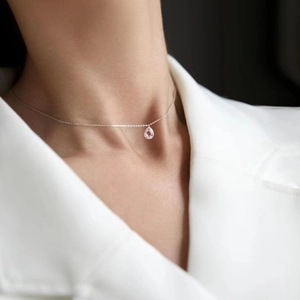 Close-up of minimalist S925 silver necklace with teardrop zirconia pendant on a model