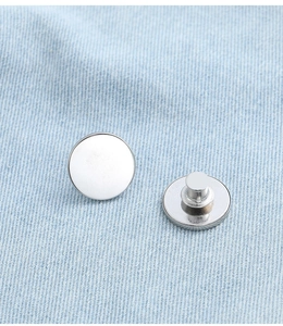 Close-up of white and silver magnetic curtain fasteners on denim fabric background