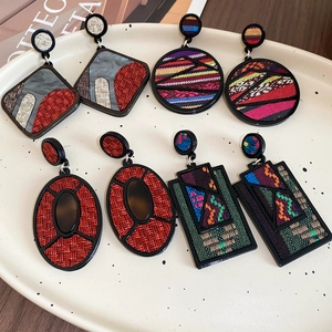 Detail view of colorful woven texture geometric acrylic earrings in a decorative plate