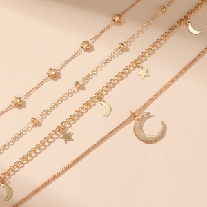 Detail of layered gold necklace featuring starfish, moon pendants and pearl bead accents