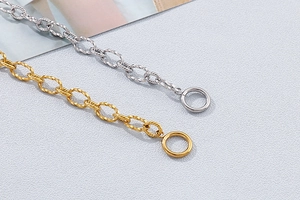 Detailed close-up of gold and silver twisted chain bracelets with OT buckle design