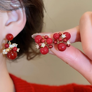 Close-up of red zircon firework earrings with gold plating and silver needles