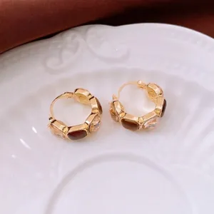 Retro amber resin and crystal U-shaped gold hoop earrings for women on a ceramic plate