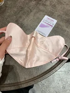Detail of soft pink silk sun protection mask with adjustable ear loops and smooth texture