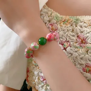 Ethnic beaded bracelet with floral ceramic beads and green accent bead on female wrist