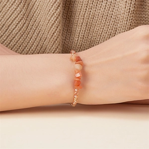 Nahaufnahme eines handgefertigten Armbands mit orangefarbenen Natursteinen