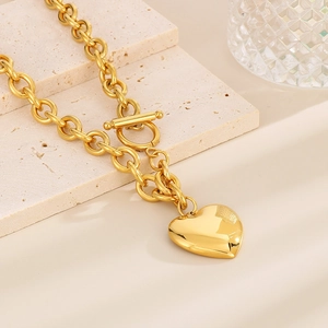 Gold chunky chain heart necklace with toggle clasp on aesthetic stone surface
