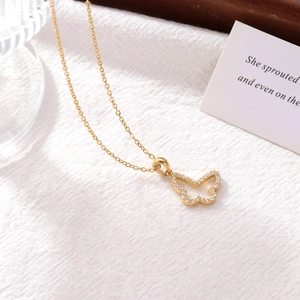 Elegant gold butterfly pendant necklace with zircon stones on warm textured background