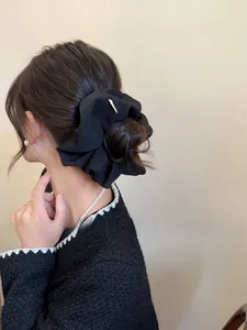 Detail of a large black rhinestone scrunchie styled in a high bun hair updo