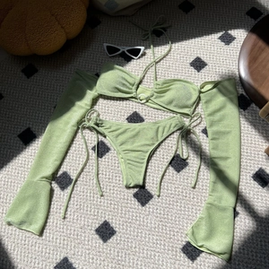 Flat lay of light green shimmer bikini with matching long sleeves and ring detail