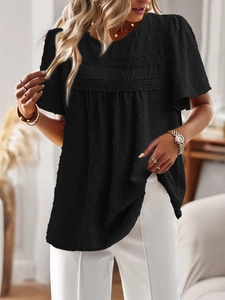 Detail view of black round neck top featuring lace patchwork and textured polka dots
