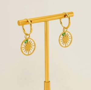 Detail of gold evil eye hoop earrings with green crystal on a display stand