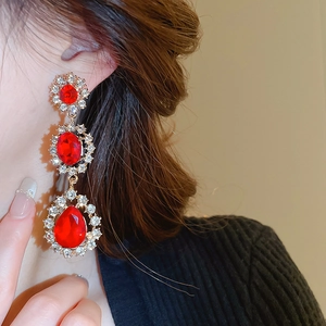 Détail de longues boucles d'oreilles vintage dorées avec cristaux rouges et strass