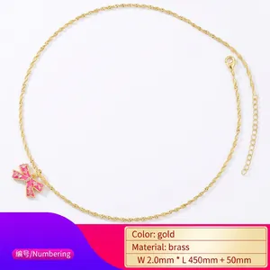 Gold necklace with pink bow pendant and white rhinestones on minimalist white background