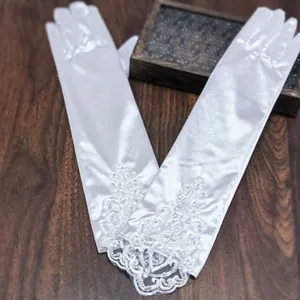 Close-up of long white satin wedding gloves with lace floral embroidery and pearl details