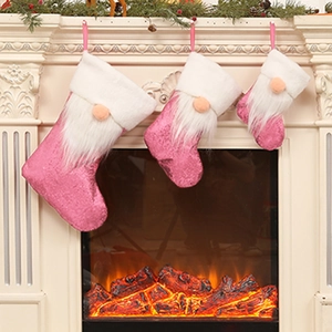 Pink sequined Christmas stockings with gnome design hanging on a festive white fireplace
