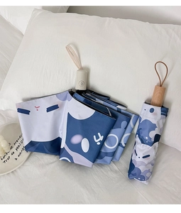 Detail of cute cat pattern folding umbrella with matching storage pouch on white bedding