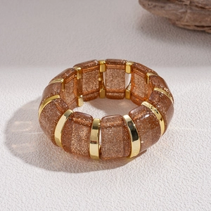 Detail of amber acrylic bracelet segments with gold glitter and metallic separators