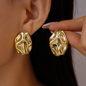 Macro shot of gold irregular textured wavy stud earrings with liquid metal visual effect