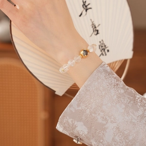 Detailed shot of a clear crystal beaded bracelet with a gold accent bead on a wrist