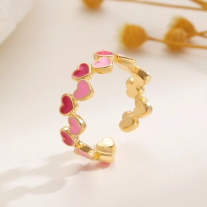 Detail eines verstellbaren Goldrings mit mehrfarbigen Herzanhängern aus Emaille in Pink