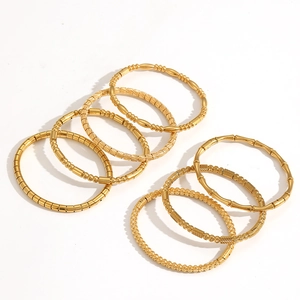 Bamboo style and twisted gold stainless steel bracelet stack on white background