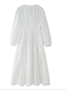 Détail d'une robe blanche à manches longues avec broderie en dentelle et taille élastique