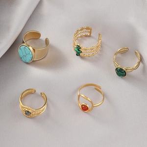Macro view of five bohemian gold plated adjustable rings with turquoise and gemstone inlays