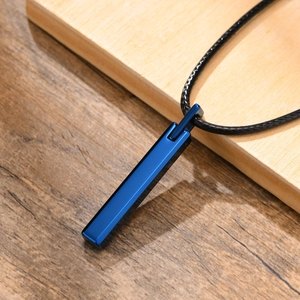 Close-up of a sleek blue tungsten pendant on a black cord with minimalist wood background