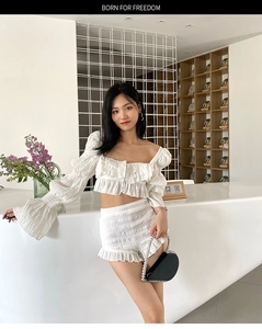 Detail of white ruffled off-shoulder crop top and shorts set with textured fabric