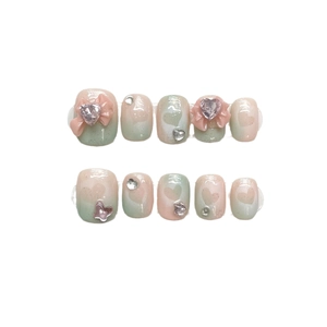 Pink and green gradient press-on nails with 3D bows and heart rhinestones on white background